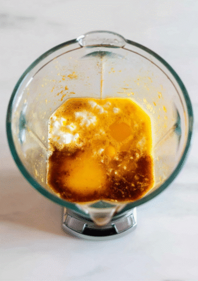 Blender filled with eggs, cottage cheese, vanilla, and oil mixture for muffins
